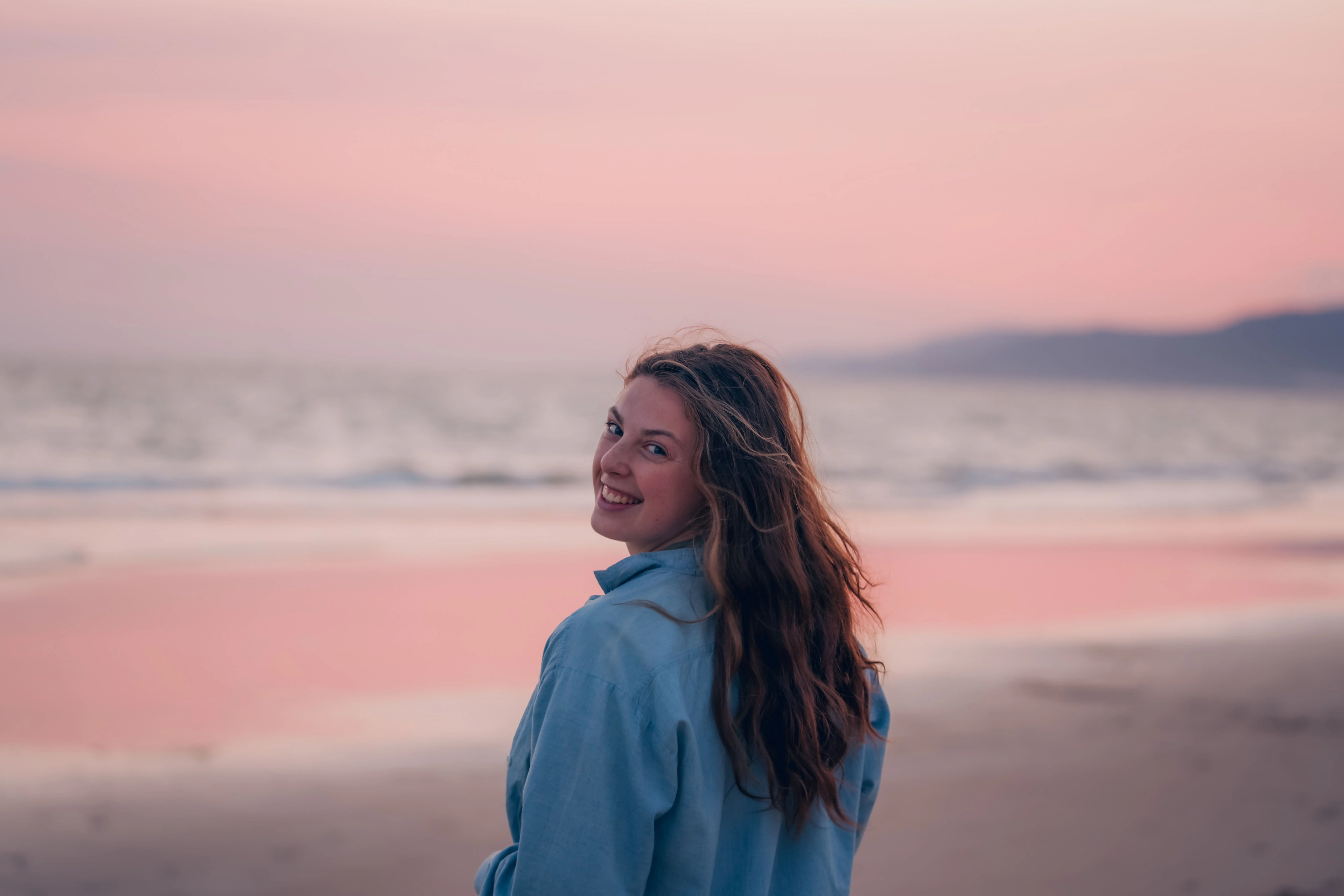 Person looking back with a smile beside the ocean